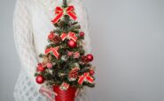 female holding christmas tree decorated with red ornaments 2