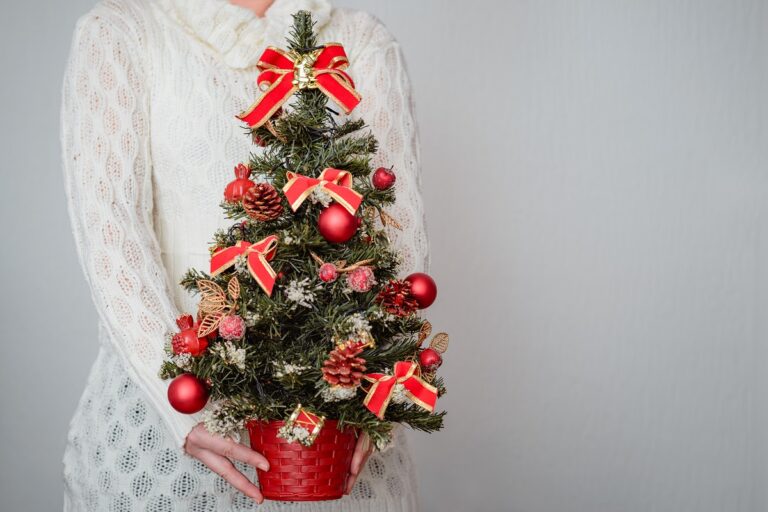 female-holding-christmas-tree-decorated-with-red-ornaments